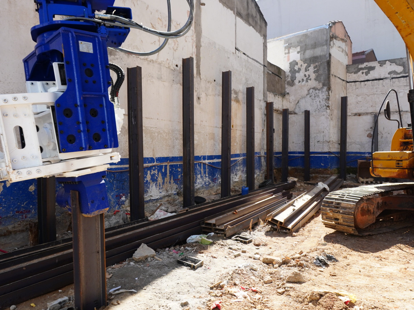 Detalhe do martelo vibratório Finkgenn e perfis metálicos no canteiro de obras